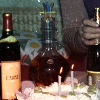 Woman and toddler near a birthday cake and wine.
