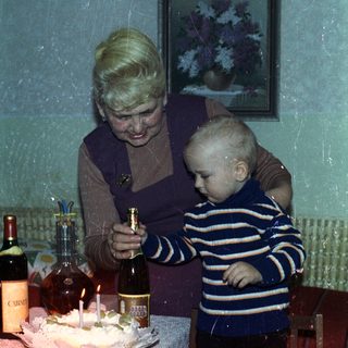 Woman and toddler near a birthday cake and wine.