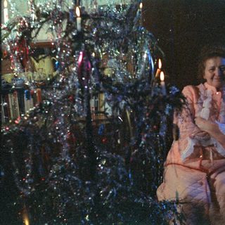 Couple sits before a brightly decorated Christmas tree.