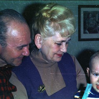 Elderly couple looking down at a young child.