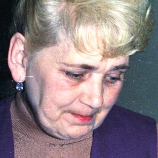 Here's a brief summary of the image: Woman with blonde hair is looking down, indoors.