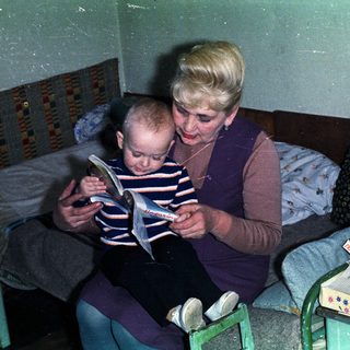 Woman reading to a young boy in a bedroom.