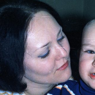 Woman embraces a young child, possibly a baby.