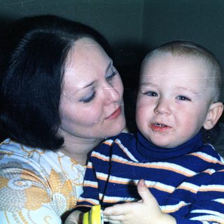 Woman embraces a young child, possibly a baby.