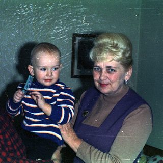 Baby being held by grandparents in a vintage-style portrait.