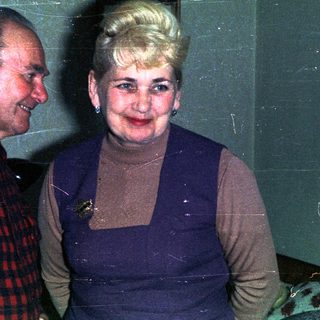 Couple poses indoors, smiling, in a vintage-style setting.