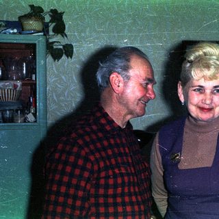 Couple poses indoors, smiling, in a vintage-style setting.