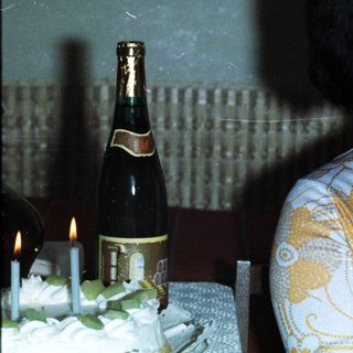 Woman holding baby, celebrating with cake and champagne.