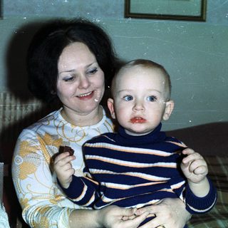 Woman holding baby, celebrating with cake and champagne.
