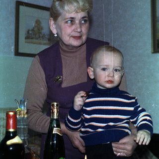 Woman holds baby, celebrating with cake and drinks.