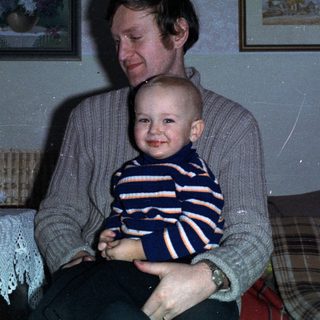 Man holding baby, celebratory scene with drinks and decorations.