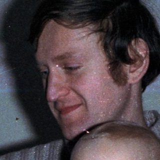 Man holding baby, celebratory scene with drinks and decorations.