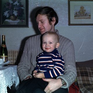 Man holding baby, celebratory scene with drinks and decorations.