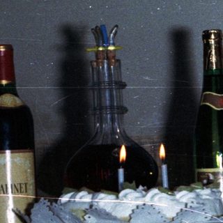 Man and child celebrating with wine and candles.
