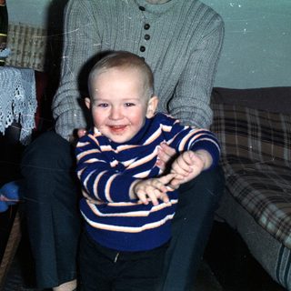 Baby boy sits on lap with celebratory food and drink.