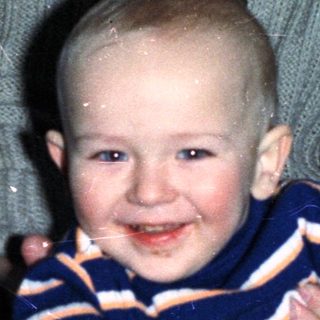 Baby boy sits on lap with celebratory food and drink.