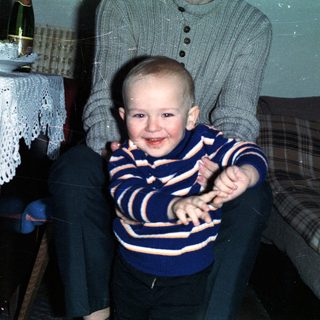 Baby boy sits on lap with celebratory food and drink.