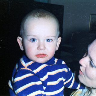 A baby and a woman are closely embracing indoors.