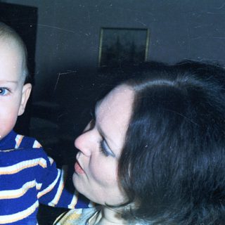 A baby and a woman are closely embracing indoors.