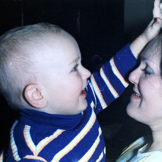 Baby playfully touches a woman's nose in a close-up.