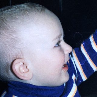 Baby playfully touches a woman's nose in a close-up.