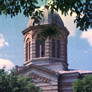 Grand church building stands amidst trees and greenery.