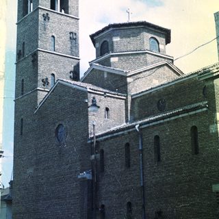 Brick church with tower and dome under a partly cloudy sky.