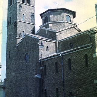 Brick church with tower and dome under a partly cloudy sky.