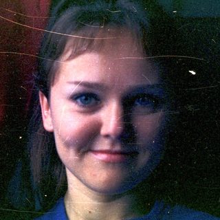 Portrait of a young woman with blue eyes and red backdrop.
