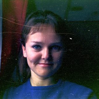 Portrait of a young woman with blue eyes and red backdrop.