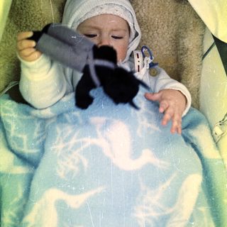 Baby in a stroller plays with a black toy.
