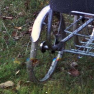 Woman crouches near a baby in a stroller outdoors.