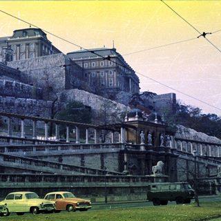 Palace elevated above a road with vintage cars.