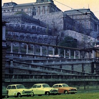 Palace elevated above a road with vintage cars.
