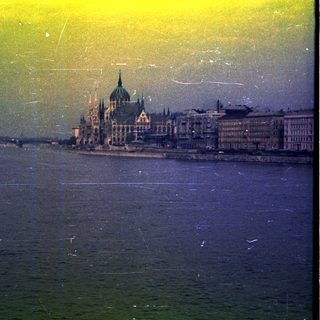 River view of buildings, likely the Hungarian Parliament.
