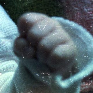 Baby lying wrapped in a blanket, looking at the camera.