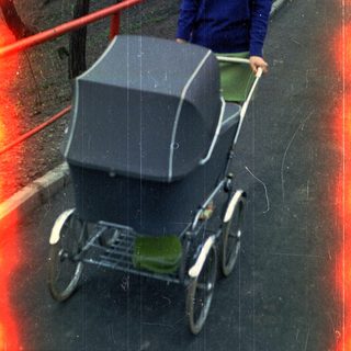 Woman pushing a vintage stroller along a paved path.