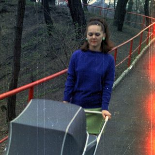 Woman pushing a vintage stroller along a paved path.