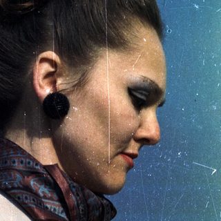 Woman in a coat and patterned scarf, side profile.