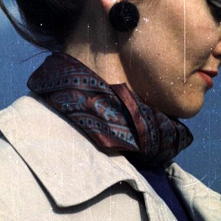 Woman in a coat and patterned scarf, side profile.
