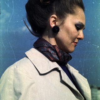 Woman in a coat and patterned scarf, side profile.