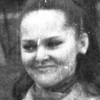 Woman stands outdoors on a rainy day, smiling.