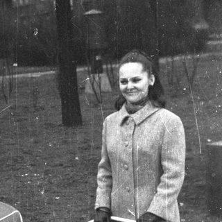 Woman stands outdoors on a rainy day, smiling.