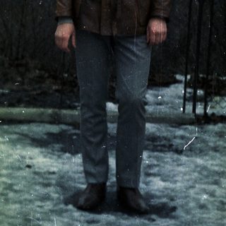 Man stands outdoors in a leather jacket and jeans.
