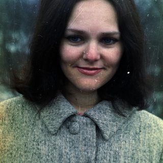 Here's a brief summary of the image: Woman with dark hair and blue eyes wearing a sweater.