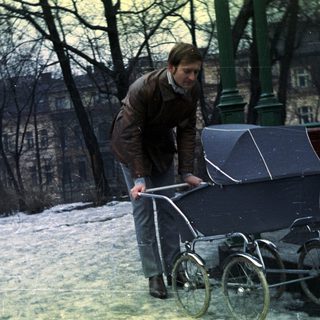 Man pushes a pram across a snowy landscape.