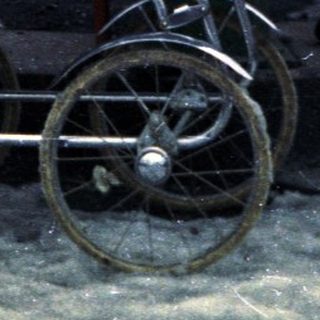 Woman stands in snow, pushing an antique baby carriage.