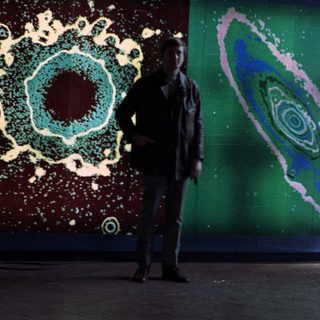 Man stands before colorful, circular splash art display.