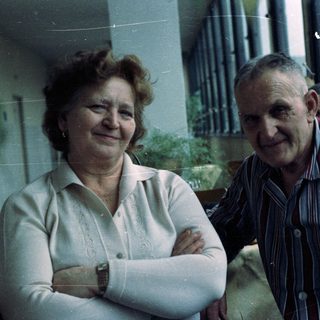 A smiling elderly couple poses for a casual portrait.