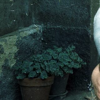 A mother sits holding her baby outdoors.